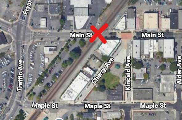 Satellite map of Main Street and Cherry Avenue intersection with a large red X marking the railroad crossing on Main Street.